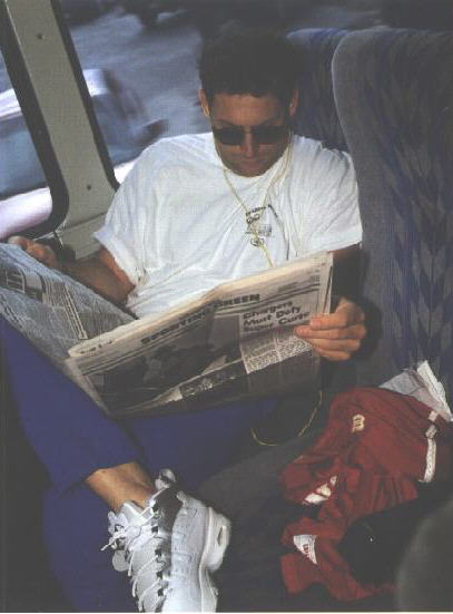 Steve on a bus listening to music & reading a newspaper